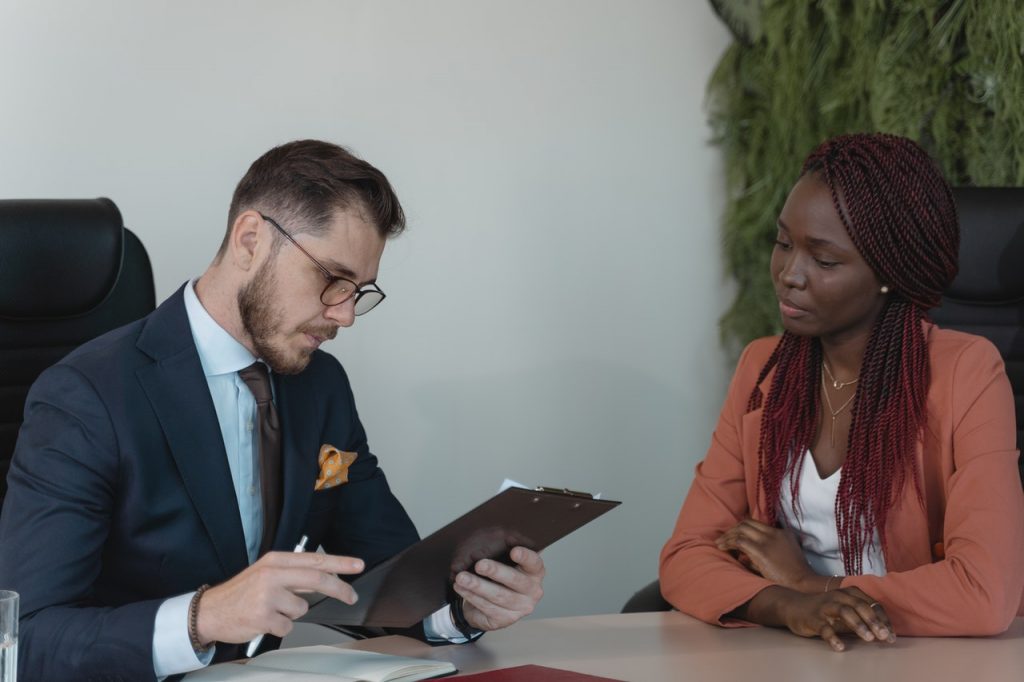 man looking at clipboard talking to woman